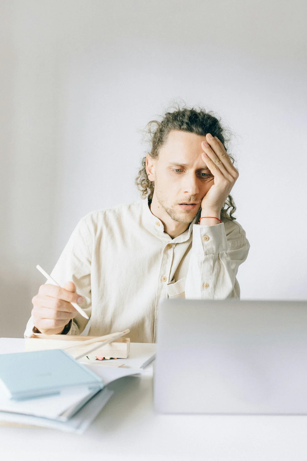 Adult male sitting in front of a computer, rubbing head stressed.