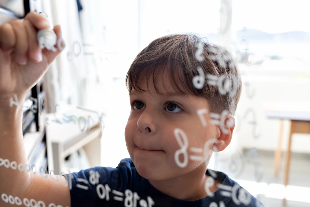 Young boy writing math, very smart and neurodivergent.